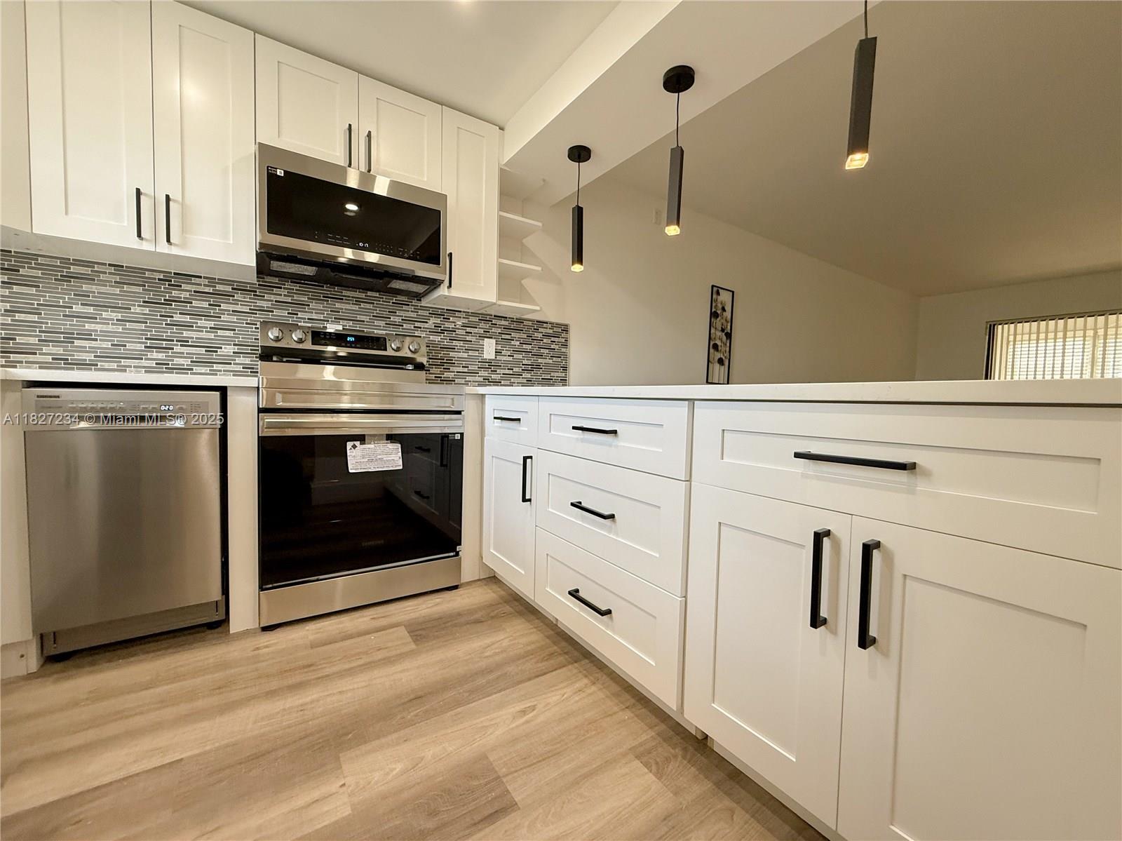 9355 Southwest 8th Street, Unit 402 Boca Raton, FL 33428 - Photo 12 of 29 a kitchen with white cabinets appliances and a sink