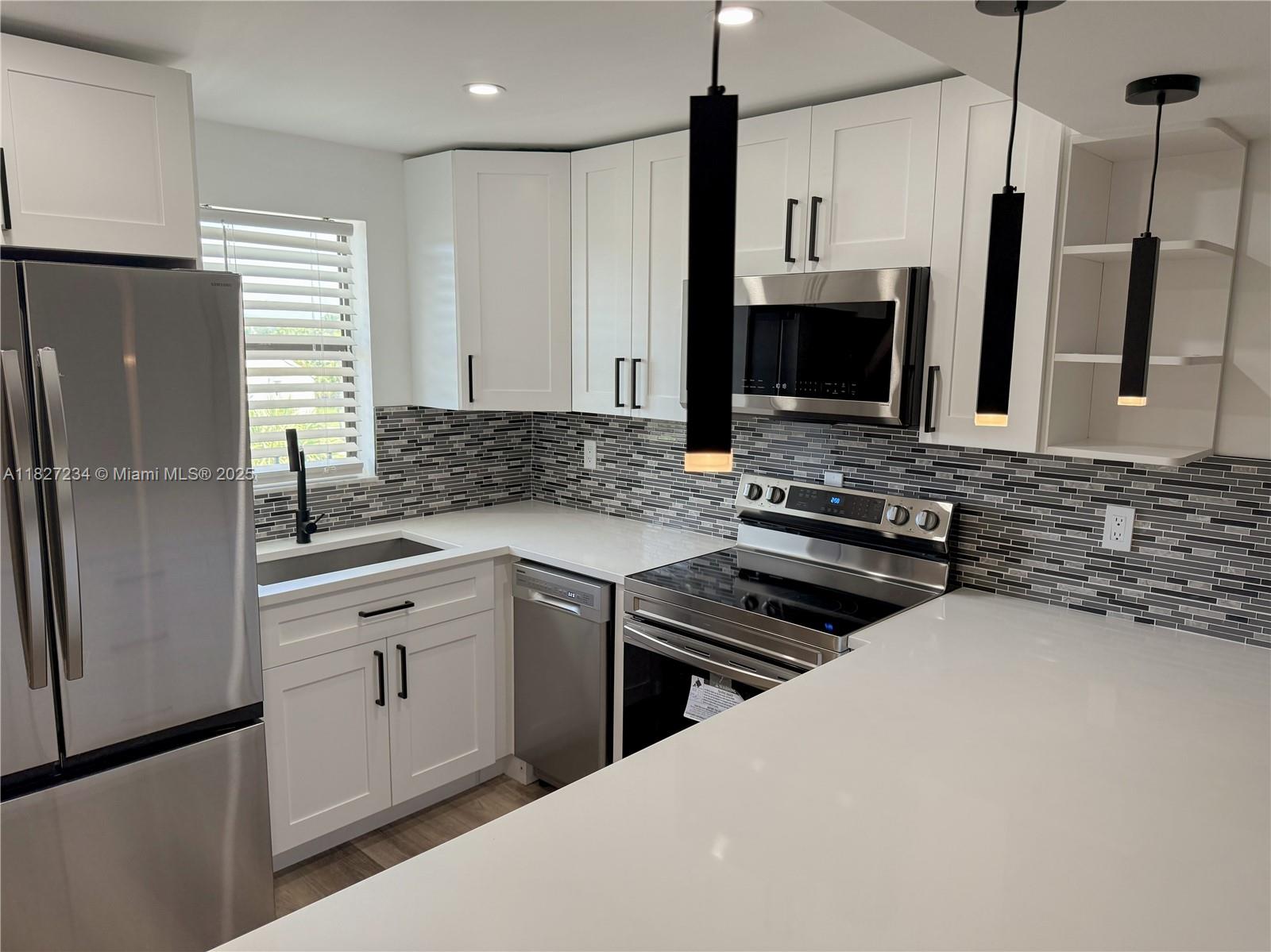 9355 Southwest 8th Street, Unit 402 Boca Raton, FL 33428 - Photo 2 of 29 a kitchen with stainless steel appliances a stove sink microwave and refrigerator