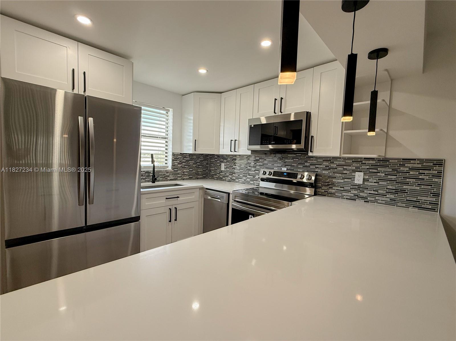 9355 Southwest 8th Street, Unit 402 Boca Raton, FL 33428 - Photo 4 of 29 a kitchen with stainless steel appliances a refrigerator sink and microwave