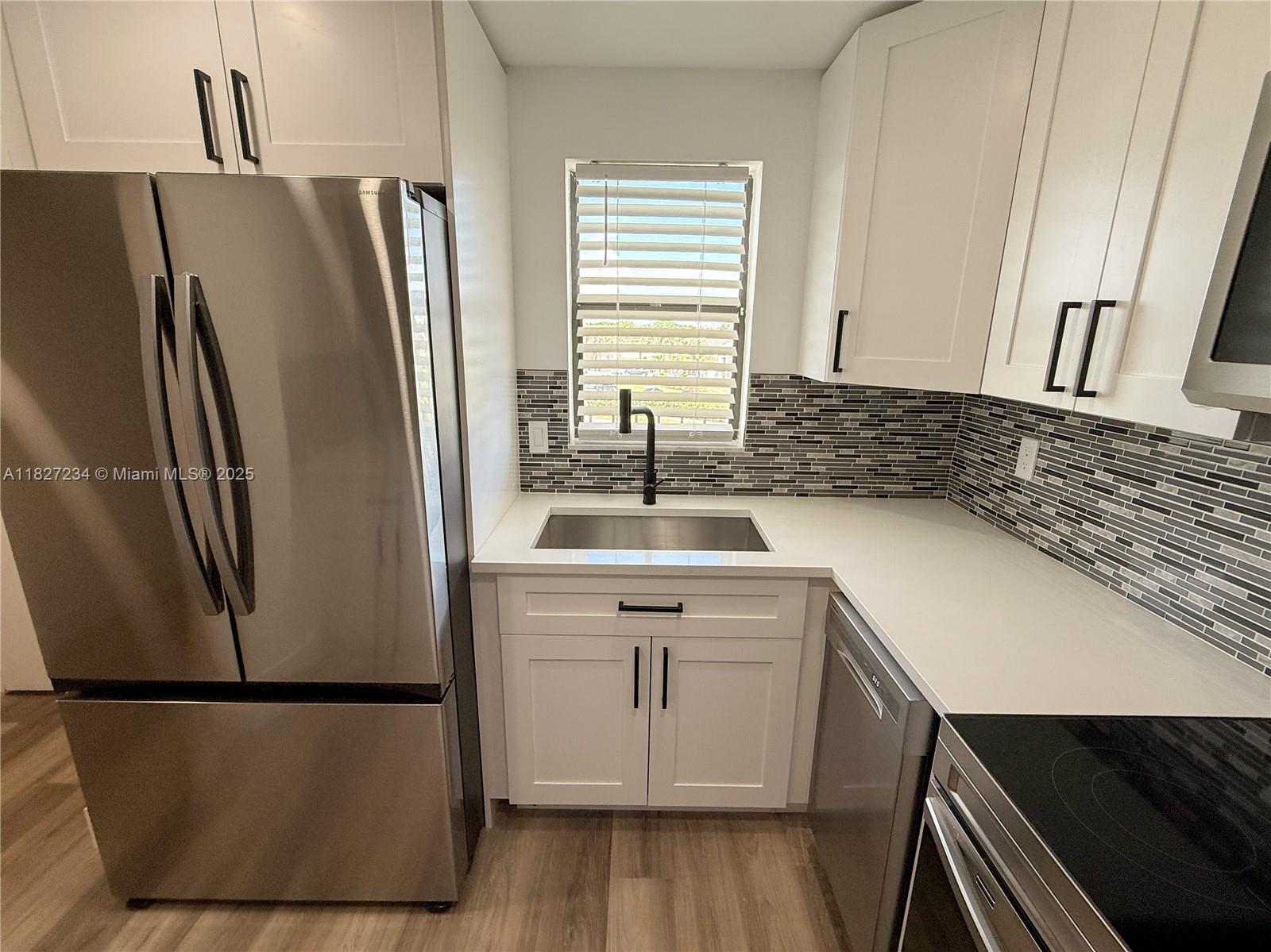 9355 Southwest 8th Street, Unit 402 Boca Raton, FL 33428 - Photo 7 of 29 a kitchen with a sink a refrigerator and a stove