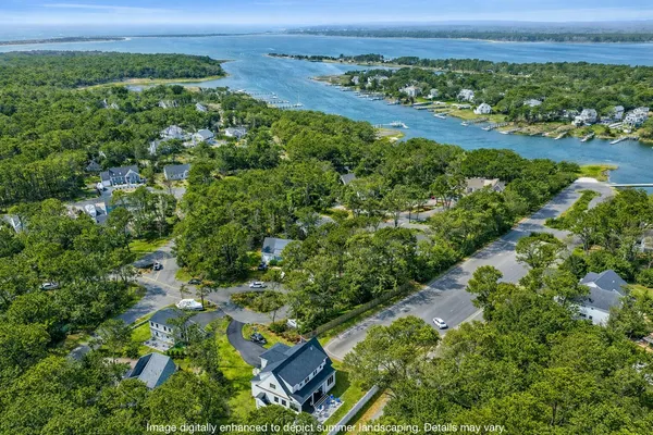 an aerial view of a residential houses with outdoor space and trees all around