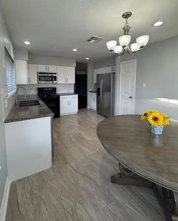 a kitchen with stainless steel appliances granite countertop a refrigerator a stove and a sink