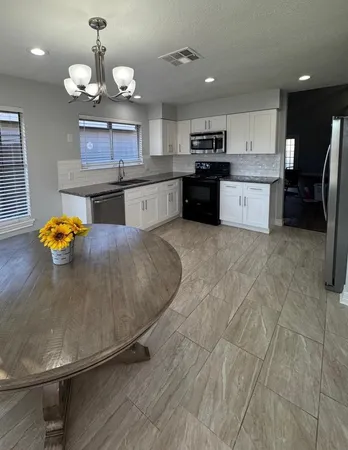 a large kitchen with stainless steel appliances kitchen island granite countertop a sink a stove and a granite counter top