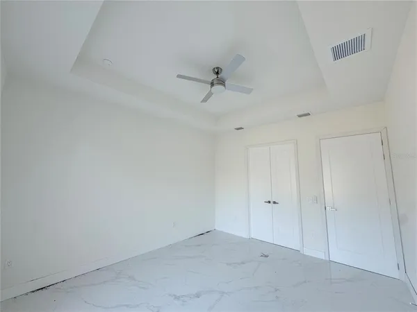 an empty room with windows and fan