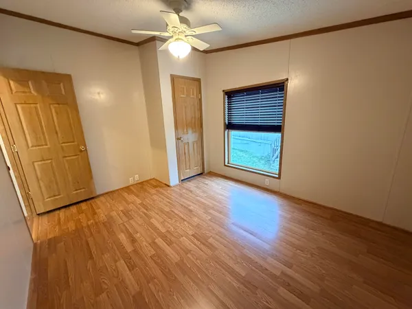 a view of an empty room with a window and wooden floor