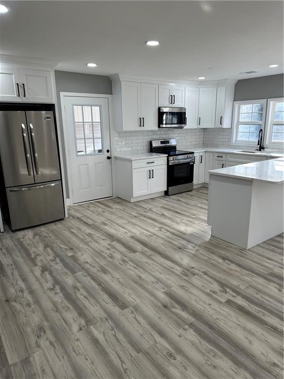 404 Walker Drive Monroe, GA 30655 - Photo 4 of 5 a large kitchen with granite countertop a stove top oven a sink dishwasher and a refrigerator with wooden floor