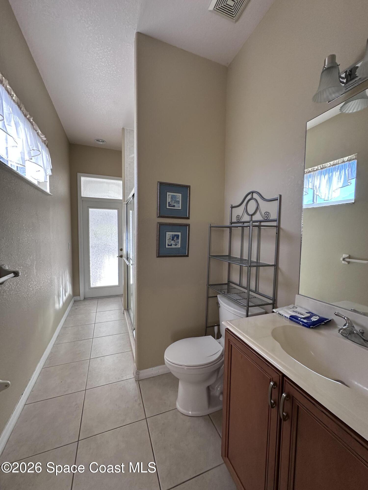 883 Spring Oak Drive Melbourne, FL 32901 - Photo 37 of 43 a spacious bathroom with a granite countertop sink a toilet a mirror and a shower