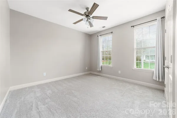 an empty room with windows and ceiling fan