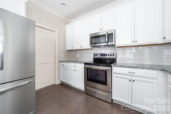 a kitchen with stainless steel appliances granite countertop grey cabinets a stove a microwave and a refrigerator