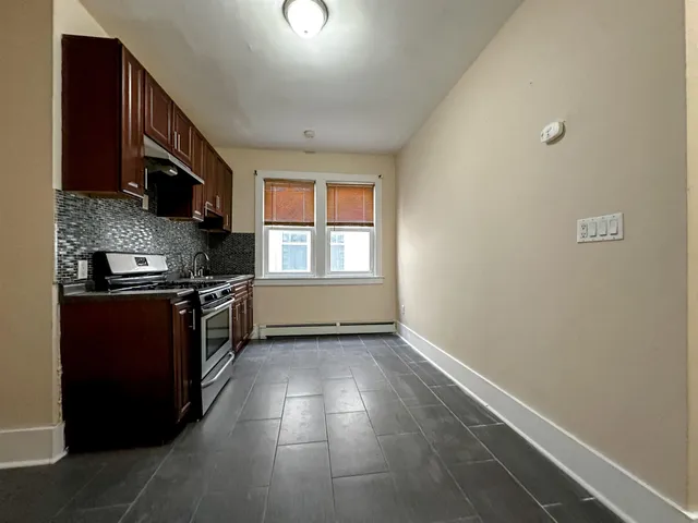 a kitchen with granite countertop a refrigerator and a stove top oven