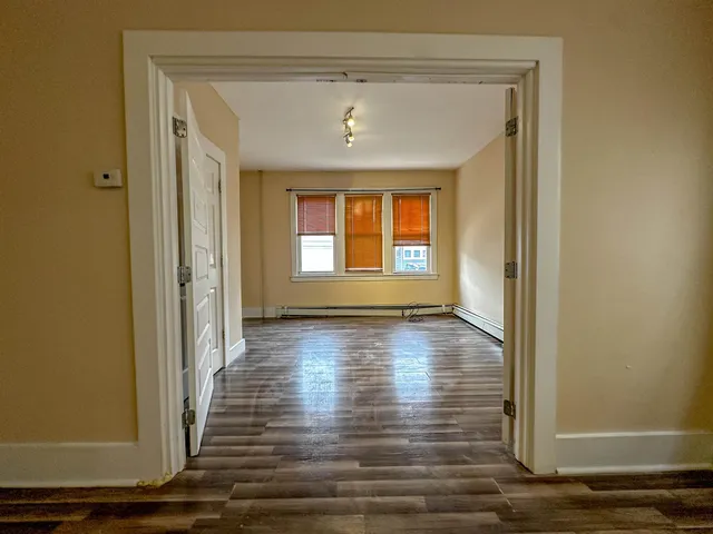 a view of an empty room with wooden floor and a window