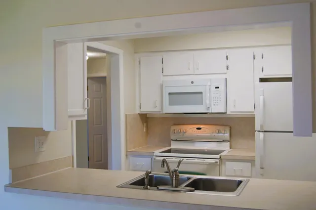 a kitchen with a refrigerator and white cabinets