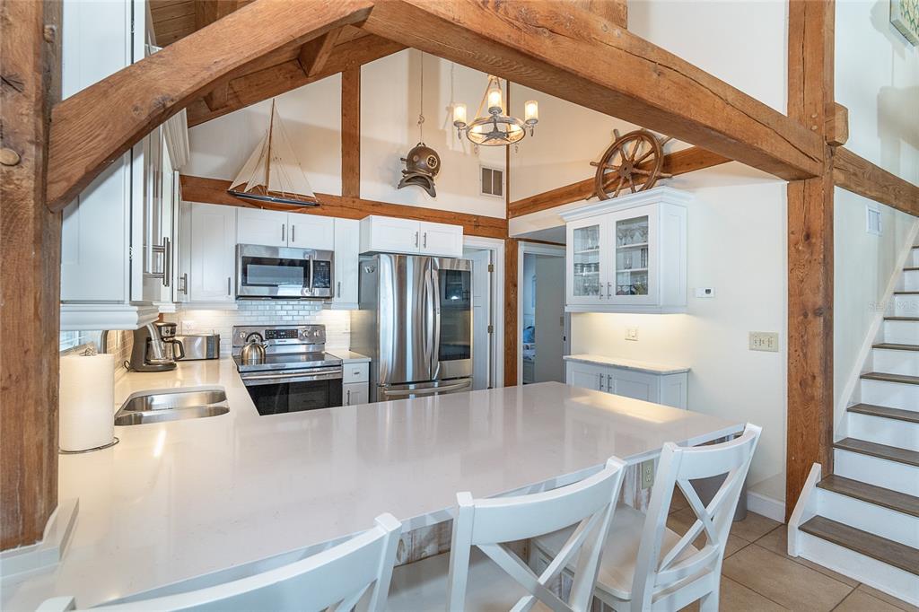 360 South Gulf Boulevard Boca Grande, FL 33921 - Photo 12 of 64 a kitchen with stainless steel appliances a stove a refrigerator a kitchen island with white cabinets and chandelier