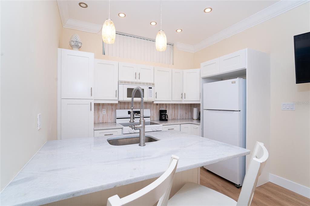 360 South Gulf Boulevard Boca Grande, FL 33921 - Photo 38 of 64 a kitchen with kitchen island a stove a refrigerator and white cabinets