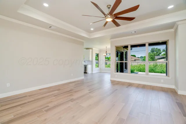 a view of an empty room with a window and wooden floor