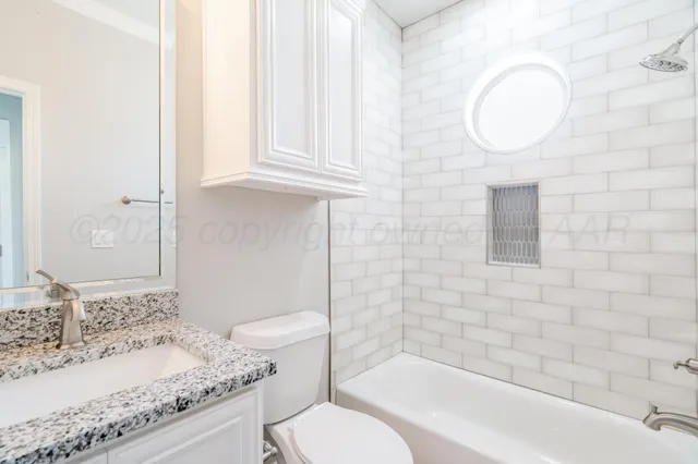 a bathroom with a granite countertop sink mirror vanity and toilet