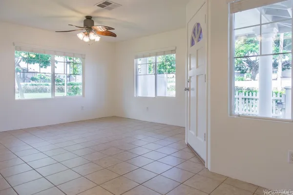 an empty room with windows and chandelier fan