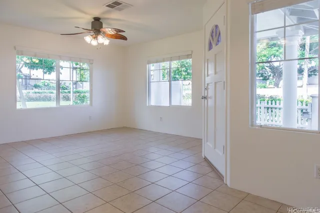 an empty room with windows and chandelier fan