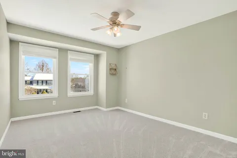 an empty room with a chandelier fan and windows