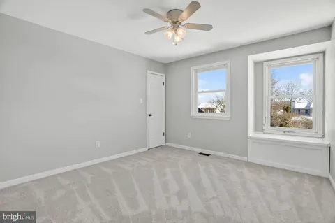 a view of an empty room with a window and a ceiling fan
