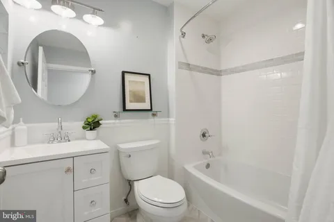 a bathroom with a toilet a sink a tub and a mirror