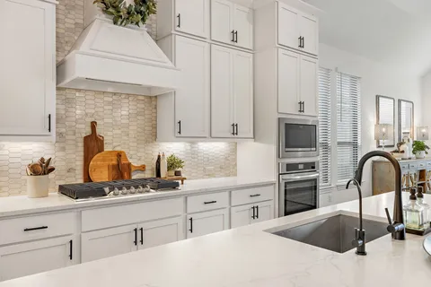 a kitchen with white cabinets and sink