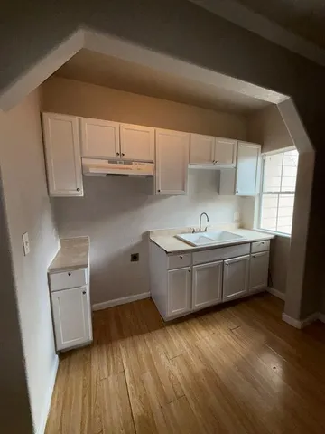 a kitchen with granite countertop a sink cabinets and wooden floor