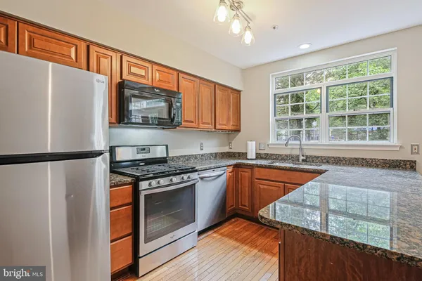 a kitchen with stainless steel appliances granite countertop a refrigerator a stove a sink and a microwave