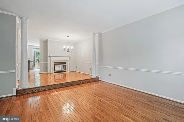 a view of an empty room with wooden floor and a fireplace