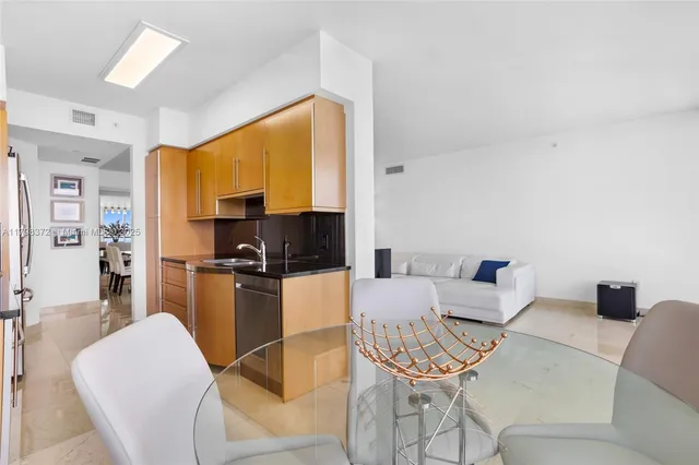 a living room with furniture a flat screen tv and a refrigerator
