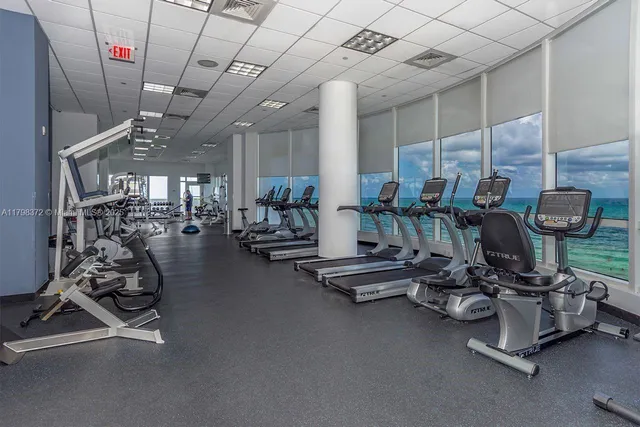a room with gym equipment and large windows