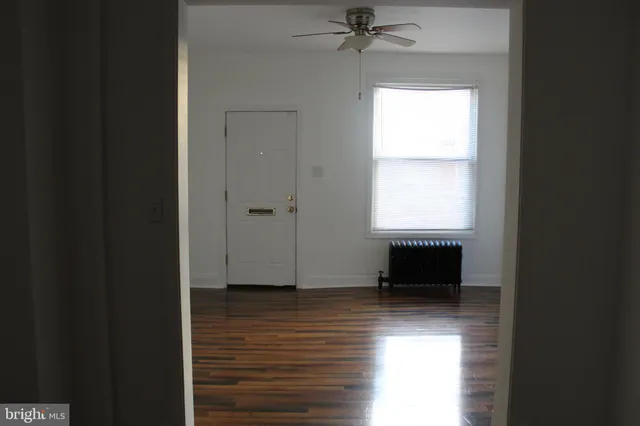 a view of an empty room with a window and wooden floor
