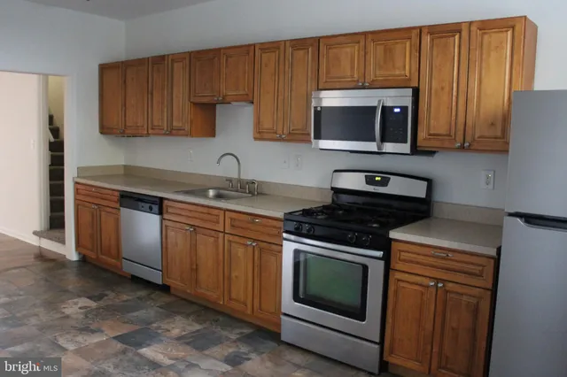 a kitchen with stainless steel appliances granite countertop wooden cabinets stove top oven and sink