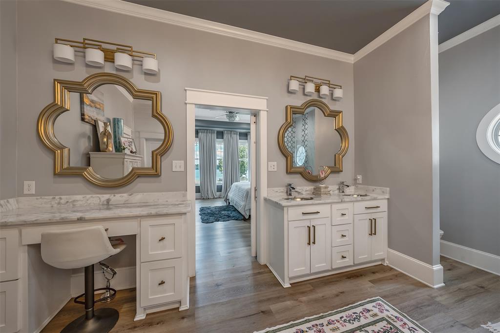 16241 Big Oak Bay Road Tyler, TX 75707 - Photo 19 of 40 Bathroom featuring dual white vanity cabinets, stone countertops, gold-framed mirrors, and wood-finish flooring