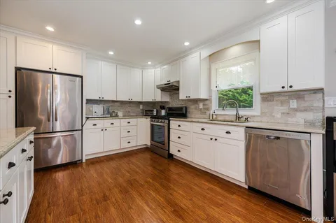 a kitchen with granite countertop white cabinets and stainless steel appliances