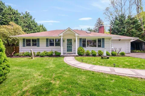 a front view of a house with a yard and potted plants
