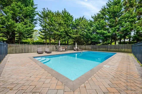a view of a swimming pool with a chair and trees