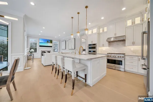 a kitchen with stainless steel appliances kitchen island granite countertop a table chairs sink and cabinets