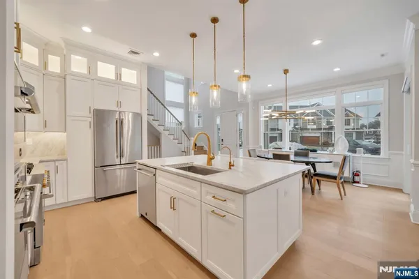 a kitchen with stainless steel appliances granite countertop a sink a stove a refrigerator and a dining table with wooden floor