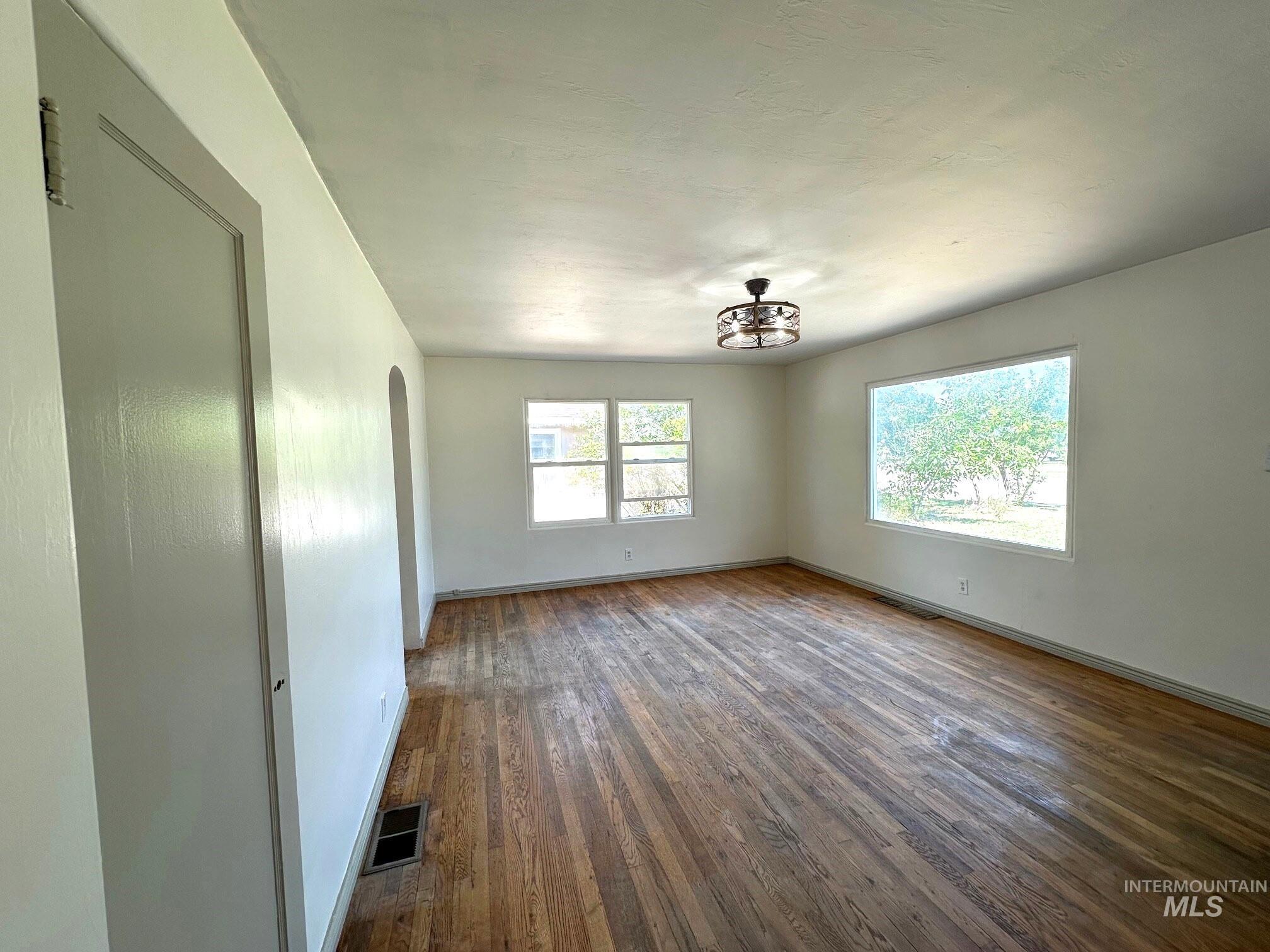 264 Southwest 10th Avenue Ontario, OR 97914 - Photo 3 of 29 Unfurnished room with arched walkways, wood finished floors, and a chandelier