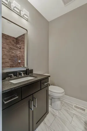 a bathroom with a granite countertop toilet sink and mirror
