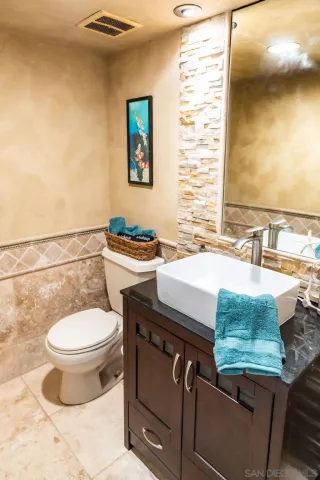 a bathroom with a granite countertop toilet a sink and a mirror