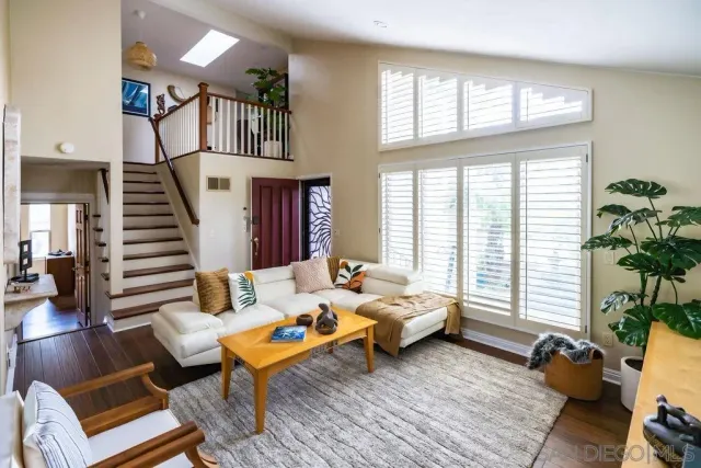 a living room with furniture floor to ceiling window and wooden floor