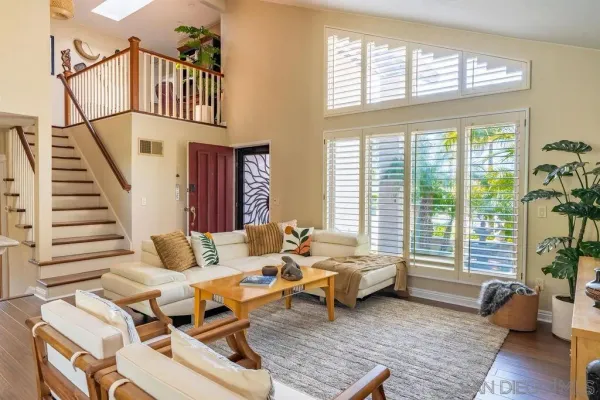 a living room with furniture floor to ceiling window and wooden floor