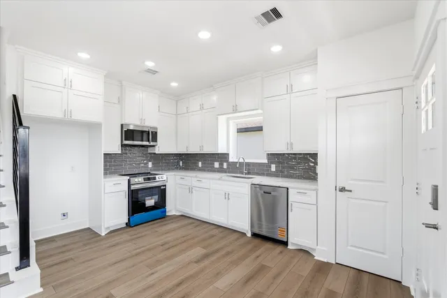 a kitchen with stainless steel appliances granite countertop a stove top oven a sink and a refrigerator