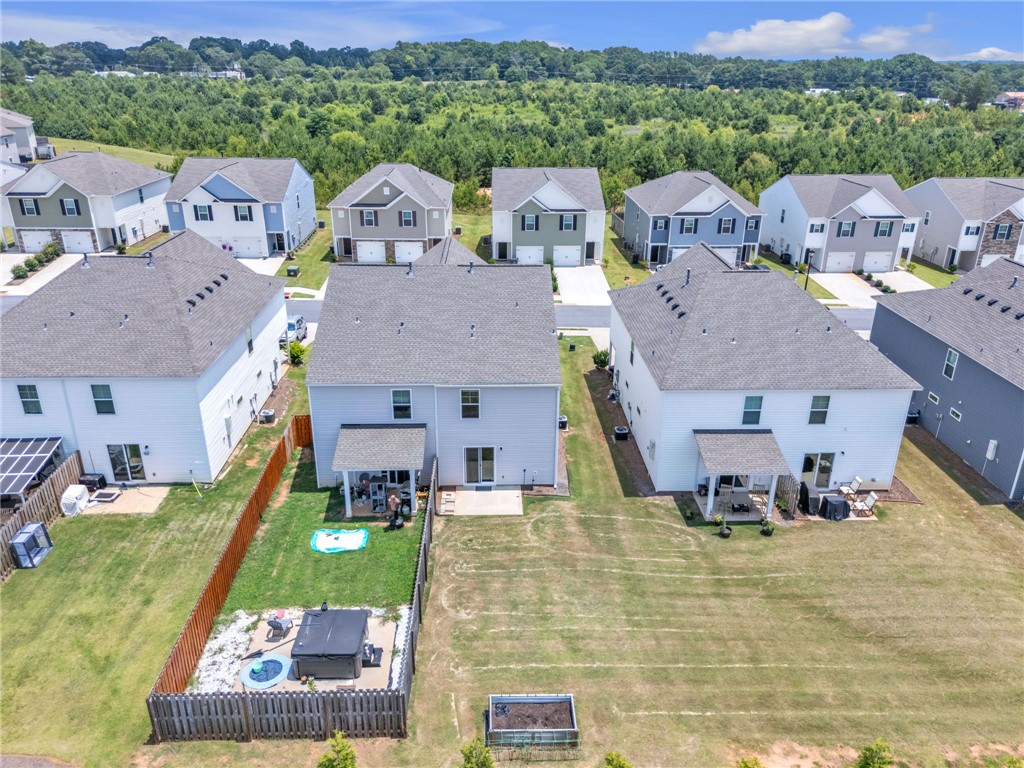 208 Samuel Street Pendleton, SC 29670 - Photo 27 of 32 An aerial perspective reveals a row of well-maintained homes with private backyards nestled against a verdant tree line.