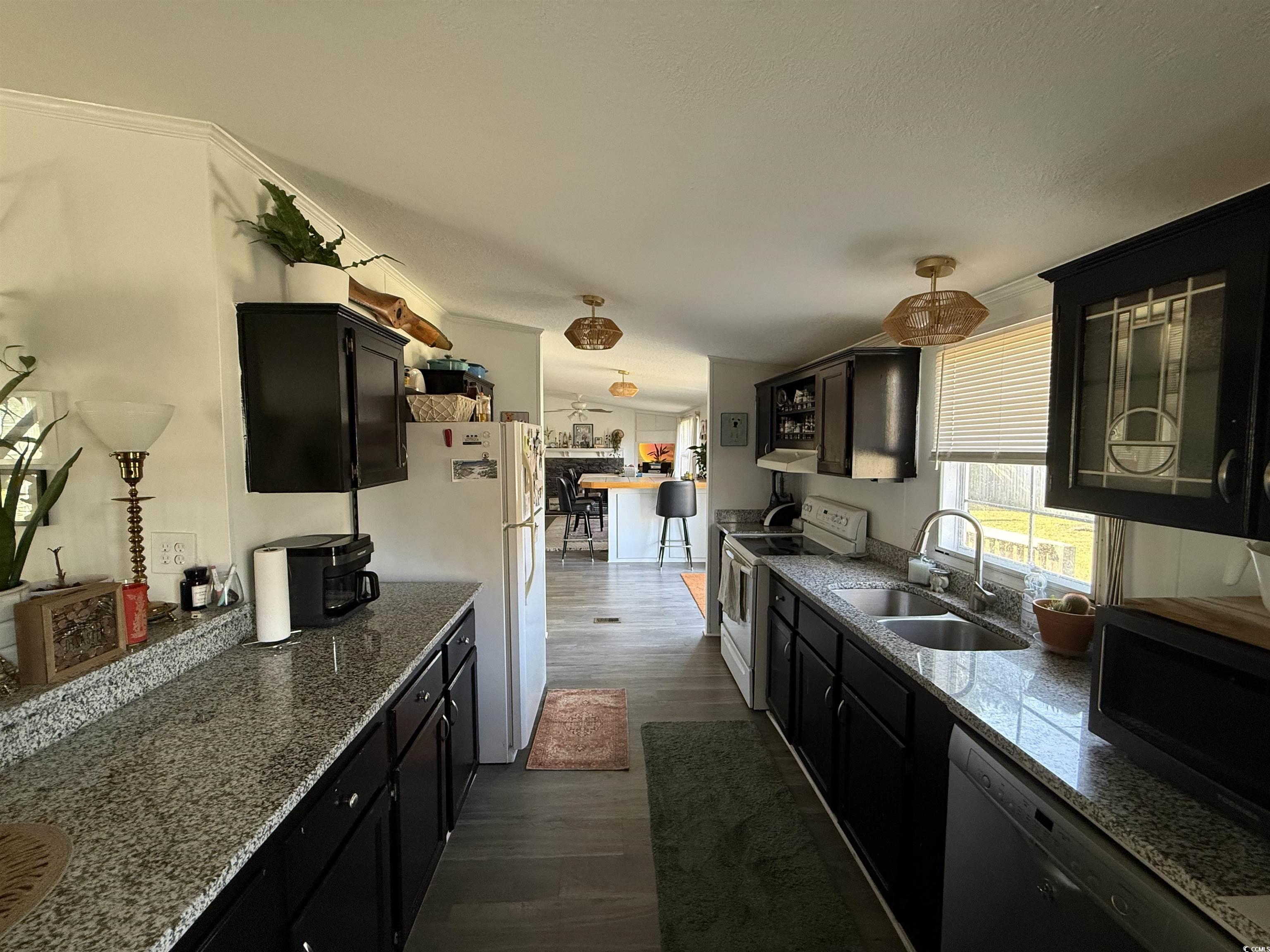 19 Gates Way Pawleys Island, SC 29585 - Photo 11 of 18 Kitchen featuring dark cabinets, white appliances, dark wood-style flooring, and light stone counters