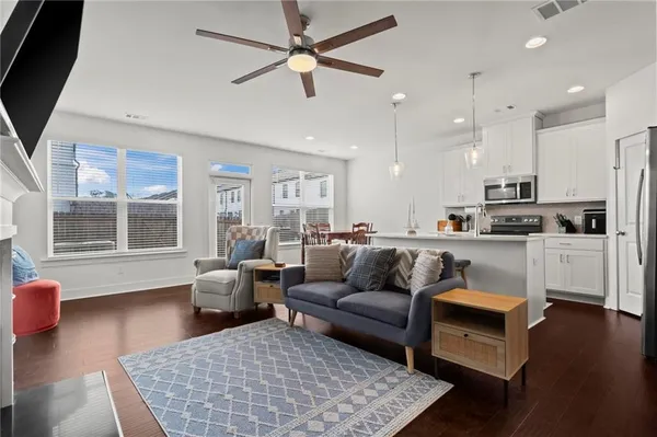 a living room with furniture kitchen view and a large window