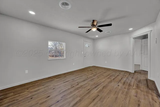 a view of empty room with wooden floor and fan