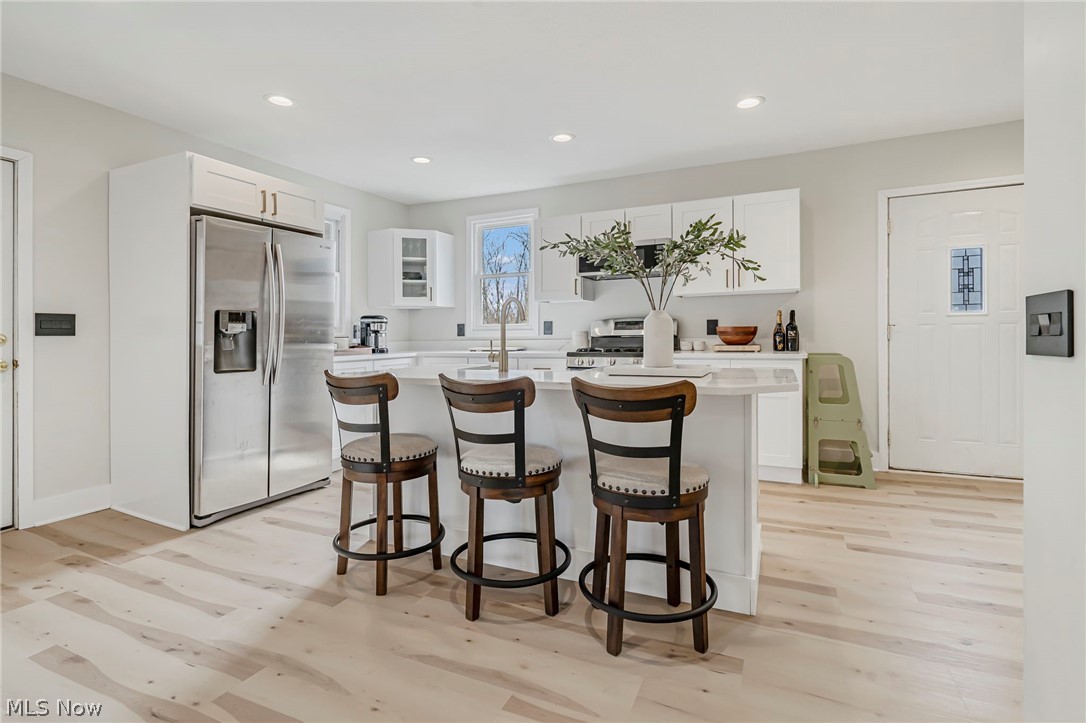 1781 Grace Road Akron, OH 44312 - Photo 5 of 26 Kitchen featuring light hardwood / wood-style flooring, stainless steel fridge, a center island, and white cabinetry